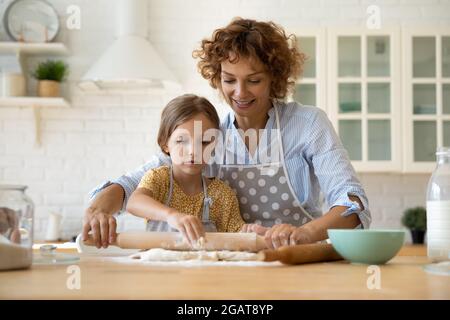 Fürsorgliche Mutter und entzückende kleine Tochter kochen in der Küche zusammen Stockfoto