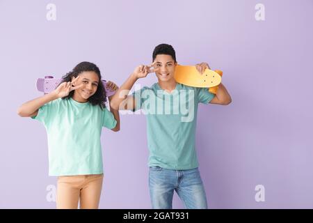 Afroamerikanischer Bruder und Schwester mit Skateboards auf farbigem Hintergrund Stockfoto