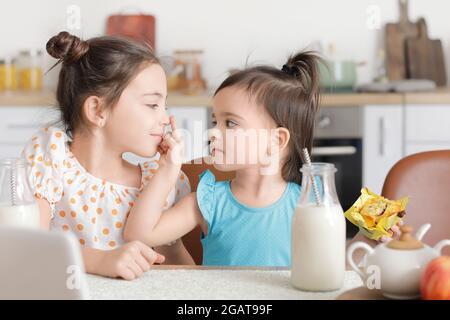 Nette kleine Schwestern mit Snack in der Küche Stockfoto