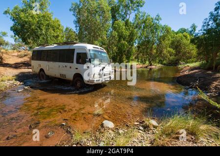 Toyota Coaster Bus Wohnmobil über einen flachen Bach im Outback, Mornington Wilderness Camp, Gibb River Road, Kimberley Region, Western Australia Stockfoto