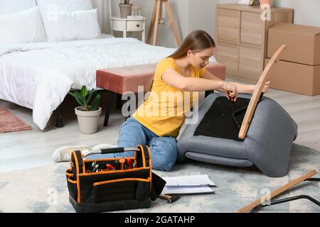 Junge Frau, die Möbel zu Hause zusammenbauen Stockfoto