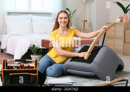 Junge Frau, die Möbel zu Hause zusammenbauen Stockfoto