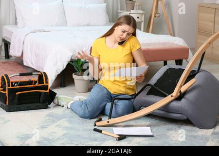 Junge Frau, die Möbel zu Hause zusammenbauen Stockfoto