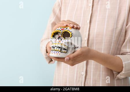 Frau mit bemaltem menschlichen Schädel für Mexikos Tag der Toten (El Dia de Muertos) auf hellem Hintergrund Stockfoto