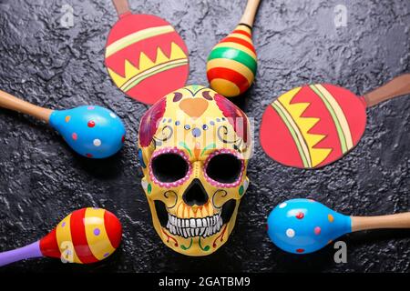 Bemalter menschlicher Schädel für Mexikos Tag der Toten (El Dia de Muertos) und Maracas auf dunklem Hintergrund Stockfoto