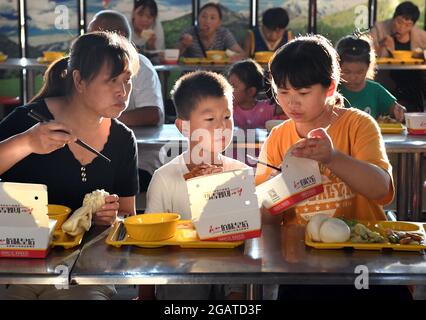 Zhengzhou, Chinas Provinz Henan. Juli 2021. Einwohner essen an einem vorübergehenden Umzugsort in einer Mittelschule im Landkreis Xunxian der Stadt Hebi, in der zentralchinesischen Provinz Henan, 29. Juli 2021. Mehr als 13.91 Millionen Menschen in 150 Regionen auf Kreisebene waren von der letzten Regengüsse seit Juli 16 betroffen. Kredit: Li An/Xinhua/Alamy Live Nachrichten Stockfoto