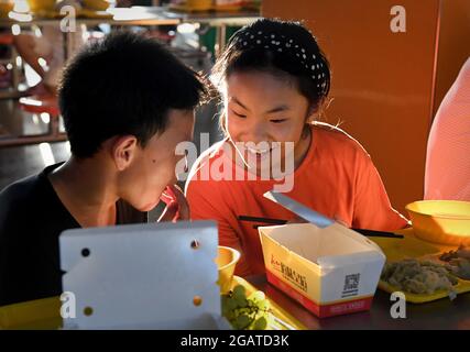 Zhengzhou, Chinas Provinz Henan. Juli 2021. Kinder essen an einem vorübergehenden Umzugsort in einer Mittelschule im Landkreis Xunxian in der Stadt Hebi, Provinz Henan in Zentralchina, 29. Juli 2021. Mehr als 13.91 Millionen Menschen in 150 Regionen auf Kreisebene waren von der letzten Regengüsse seit Juli 16 betroffen. Kredit: Li An/Xinhua/Alamy Live Nachrichten Stockfoto