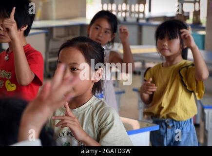 Zhengzhou, Chinas Provinz Henan. Juli 2021. Kinder lernen einen Tanz mit einem Freiwilligen an einem vorübergehenden Umzugsort in einer Mittelschule im Landkreis Xunxian der Stadt Hebi, der zentralchinesischen Provinz Henan, 29. Juli 2021. Mehr als 13.91 Millionen Menschen in 150 Regionen auf Kreisebene waren von der letzten Regengüsse seit Juli 16 betroffen. Kredit: Li An/Xinhua/Alamy Live Nachrichten Stockfoto