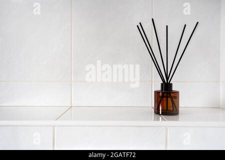 Aromatherapie-Sticks in Glasflasche in Toilette oder Bad in der Nähe von weiß gefliesten Wand mit Kopierraum, Parfüm und Bambus-Luxusprodukt Stockfoto