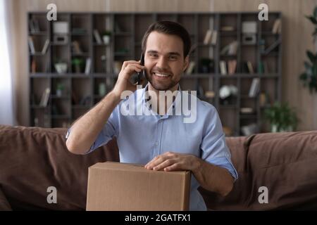 Portrait von glücklichen jungen Mann machen Telefonanruf halten Paket Stockfoto