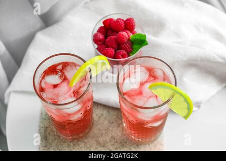Auf dem Tisch im Zimmer befinden sich Gläser leckerer Limonade und eine Schüssel mit Himbeere Stockfoto