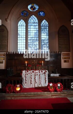 Altar der St. Mary's Church im Dorf Longnor, Shropshire, England, Großbritannien. Der Altar ist mit roten Mohnblumen für einen Gedenkgottesdienst geschmückt Stockfoto