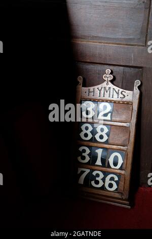 Eine dunkle Eichenhymntafel mit Nummern in einer Landkirche in Shropshire, England, Großbritannien Stockfoto