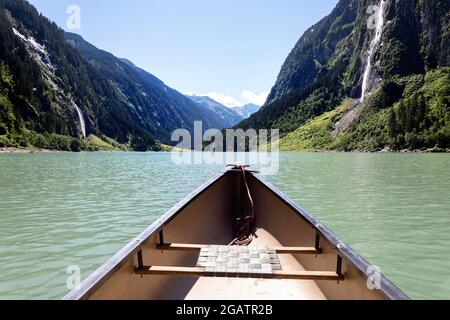 Spitze des Kanus auf Bergsee im Sommer alpine Landschaft, mit zwei Wasserfällen im Hintergrund. Stillup Stausee, Stillup Lake, Österreich, Tirol Stockfoto