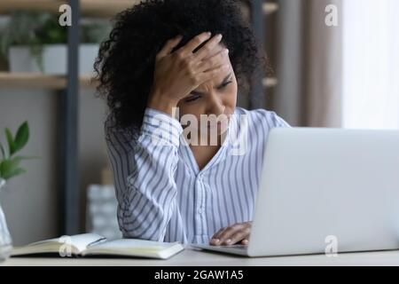 Unglückliche afroamerikanische Frau fühlt sich am Arbeitsplatz müde Stockfoto