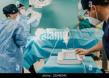 Chirurgen-Team Vorbereitung des Patienten im Operationssaal in der Privatklinik - Fokus auf die rechte Ärztehand Stockfoto