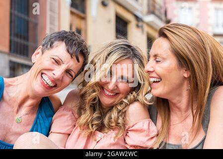 Drei lachende, reife Freunde blicken zusammen auf die Kamera Stockfoto