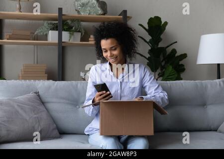 Glückliche Biracial Frau verwenden Handy überprüfen Versandstatus Stockfoto