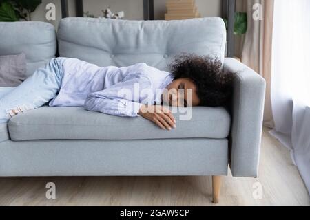 Erschöpfte Birazialfrau schläft zu Hause auf der Couch Stockfoto