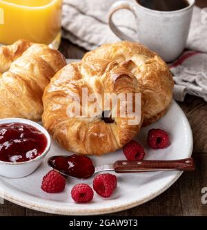 Croissants mit Himbeerkonfitüre und frischen Himbeeren auf einem Teller Stockfoto