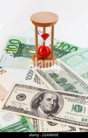 100-Dollar- und Euro-Banknoten mit Sanduhr auf weißem, isoliertem Hintergrund Stockfoto