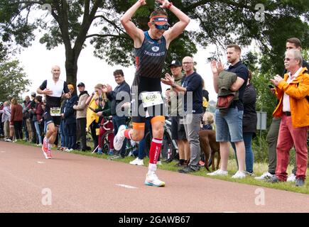 Maastricht, Niederlande. August 2021. Typ Kerkstra aus den Niederlanden, der während des letzten Teils des Ironman 70.3 Maastricht-Limburg Triathlons läuft, bringt die Menge auf seine Seite, mit einer weiteren Runde vor dem Start. Aufgrund des schnell fließenden Wassers in der Maas nach den jüngsten Überschwemmungen wurde der Schwimmabschnitt der Strecke durch einen zusätzlichen Laufabschnitt ersetzt, was den Triathlon zu einem Run-Bike-Run-Event machte. Anna Karpendale/Alamy Live News Stockfoto