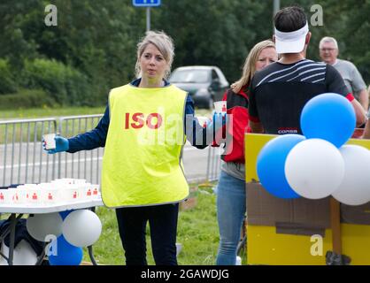 Maastricht, Niederlande. August 2021. Freiwillige geben isotonische Getränke und Wasser an Triathleten, die während des letzten Teils des Ironman 70.3 Maastricht-Limburg Triathlons laufen. Aufgrund des schnell fließenden Wassers in der Maas nach den jüngsten Überschwemmungen wurde der Schwimmabschnitt der Strecke durch einen zusätzlichen Laufabschnitt ersetzt, was den Triathlon zu einem Run-Bike-Run-Event machte. Anna Karpendale/Alamy Live News Stockfoto