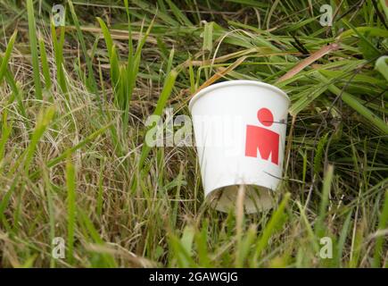 Maastricht, Niederlande. August 2021. Ein Hilfstationsbecher, der während der letzten Laufetappe des Ironman 70.3 Maastricht-Limburg Triathlons seitlich in das Gras geworfen wurde. Aufgrund des schnell fließenden Wassers in der Maas nach den jüngsten Überschwemmungen wurde der Schwimmabschnitt der Strecke durch einen zusätzlichen Laufabschnitt ersetzt, was den Triathlon zu einem Run-Bike-Run-Event machte. Anna Karpendale/Alamy Live News Stockfoto