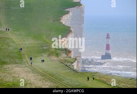 Spaziergänger auf dem South Downs Way, vorbei am Leuchtturm in Beachy Head, East Sussex, Großbritannien Stockfoto