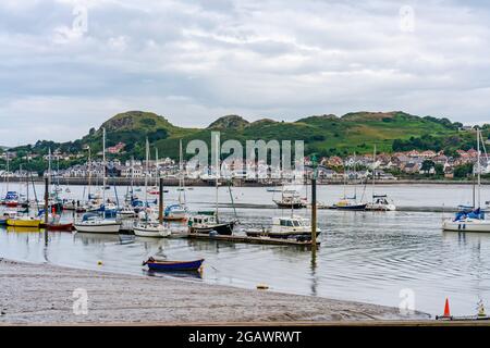 CONWY, WALES - 04. JULI 2021: Boote und Yachten in Conwy Quayside bei Ebbe und Blick über die Mündung nach Deganwy. Stockfoto