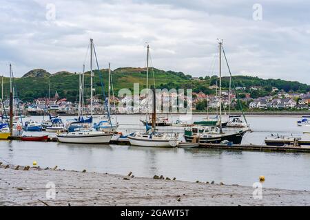 CONWY, WALES - 04. JULI 2021: Boote und Yachten in Conwy Quayside bei Ebbe und Blick über die Mündung nach Deganwy. Stockfoto