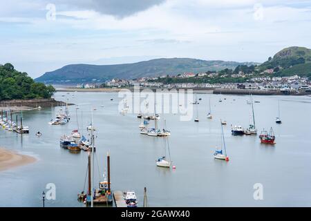 CONWY, WALES - 04. JULI 2021: Conwy Quayside bei Ebbe und Blick über die Mündung zum Deganwy Stockfoto