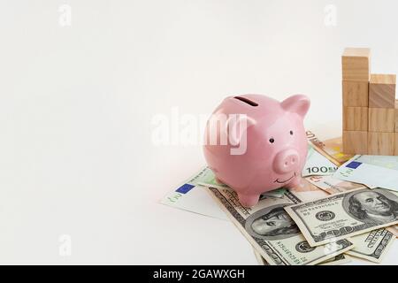 Panorama Schwein geformtes Sparschwein, wachsende Graph Holzwürfel, Euro-Banknoten und US-Dollar auf isoliertem weißem Hintergrund Stockfoto