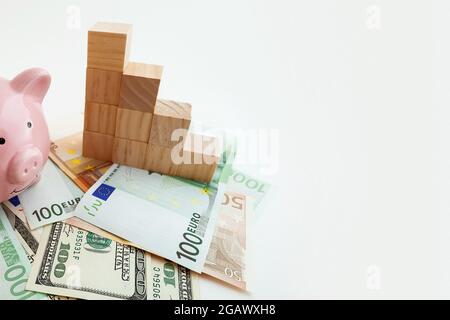 Panorama Schweinebank, Bitcoin-Münzen, wachsende Holzwürfel, Euro-Banknoten und US-Dollar auf isoliertem weißem Hintergrund Stockfoto