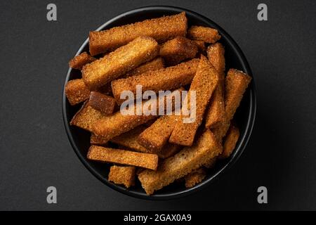 Schale aus Roggencroutons auf schwarzem Hintergrund Stockfoto