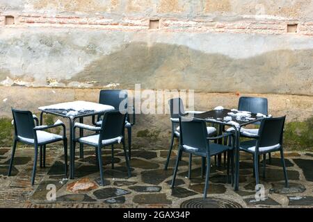 Tische und Stühle auf einer schneebedeckten Terrasse einer Bar. Stockfoto