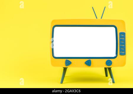 Vintage Miniatur-Spielzeug-Fernseher auf gelbem Hintergrund. Stockfoto