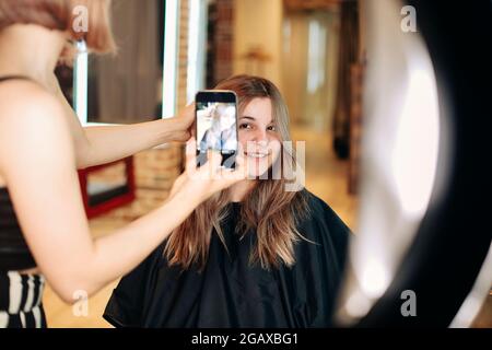 Der professionelle Friseur macht ein Foto von Mädchen, die neue Frisur schneiden Stockfoto