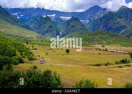 Touristenauto mit Kajaks auf dem Gipfel in einer wunderschönen Landschaft eines kultivierten Plateaus zwischen einer Biegung im Fluss Vjosa und den Bergen, Permet, Albanien Stockfoto