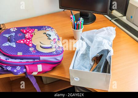 Auf dem Computertisch befinden sich eine Schultasche und neue Schuhe Stockfoto