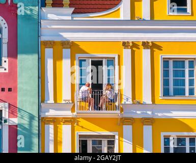 Timisoara, Rumänien - 06.19.2021: Mann und Frau sitzen auf einem kleinen Balkon eines alten farbigen Gebäudes mitten im Zentrum von Timisoara Stockfoto
