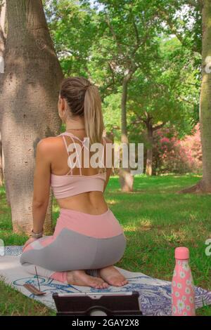 Vertikale Bild Rückansicht junge Frau genießen kühlen Pilates Übung im Stadtpark nach dem Training. Pilates Outdoor Workout 2021. Stockfoto