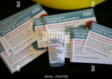 Eine Ampulle mit Impfstoffen von Moderna Covid-19 und Impfprotokollkarten in einem Impfzentrum in London. Stockfoto