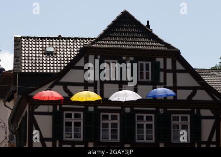 Bunte Regenschirme hängen an einem Seil zwischen Häusern oberhalb der Fußgängerzone von Bad Kreuznach, Rheinland-Pfalz, Deutschland. Stockfoto