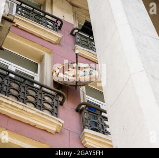 Rostige Parabolantenne in Form einer Schale, die an der Wand zwischen Balkonen angebracht ist, St. Petersburg, Russland Stockfoto