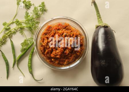 Ein feuergeröstetes Gericht mit Zwiebeln, Tomaten und Gewürzen. Allgemein bekannt in Indien als Baingan bharta. Aufgenommen auf weißem Hintergrund. Stockfoto