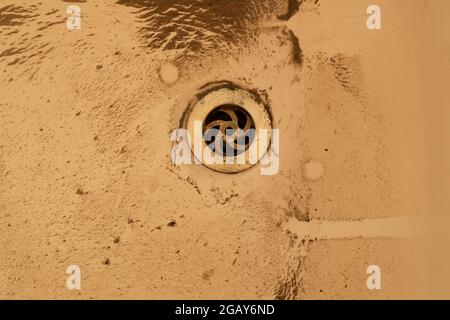 Bad, Boden, Boden mit Schmutzmuster, Detritus, Sand, Schmutz, der schmutziges Wasser hinterlässt, Tropfstellen, die aus einem Steckloch entweichen. Stockfoto