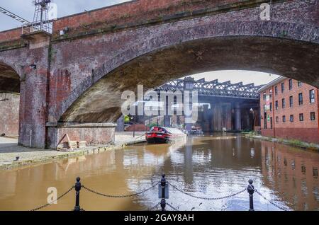 Narrowboat, das am roten Backsteinviadukt der Castlefield-Eisenbahn auf dem Bridgewater-Kanal in Castlefield, Manchester, Nordwestengland, Großbritannien, festgemacht ist Stockfoto