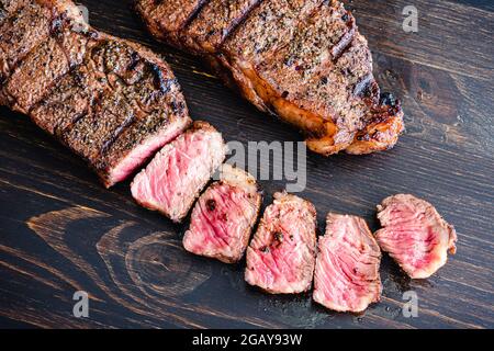 Gegrilltes NY Strip Steak mit Kaffeerub: Gegrillte New York Strip Steaks auf dunklem Holz Stockfoto