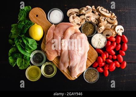 Italienische Pfanne Huhn mit Tomaten und Pilzen Zutaten: Rohe Hühnerschnitzel, Pilze, Traubentomaten und andere Zutaten für eine rustikale IT Stockfoto